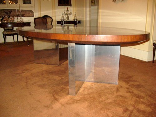 Dunbar Dining or Conference Table Mid to late 70s Designed by Roger Lee Sprunger, a protege of Edward Wormley An iconic piece wth high mirrored pristine finish of Brazilian Rosewood with Mahogany banned edges.  Polished Chrome Planks â€“ Plinths V shaped bases and middle secret drawer with Brass Dunbar tag.  Oval in shape and measuring 110 in. x 60 in.     - Extraordinary Auction - Nike Spillson Home Interiors & Furnishings